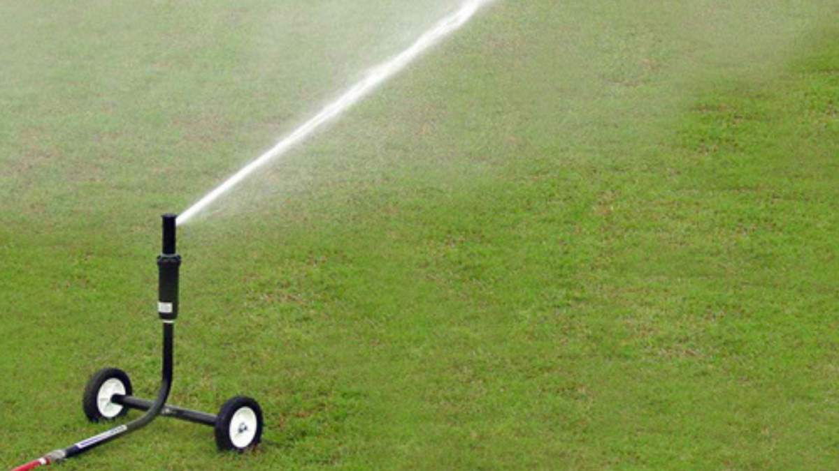 Green yard with the 1000R wheeled sprinkler cart up close spraying out across it